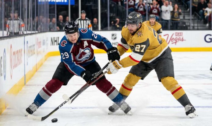 vegas-golden-knights-colorado-avalanche-2026 An action shot of Nathan MacKinnon (#29) of the Colorado Avalanche battling Shea Theodore (#27) of the Vegas Golden Knights in a crucial playoff game face-off.