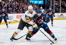 How to Watch Vegas Golden Knights at Colorado Avalanche Game 1 Tonight An intense photo capturing a puck battle between superstars Jack Eichel (#15) of the Vegas Golden Knights and Nathan MacKinnon (#29) of the Colorado Avalanche during Game 1 of the 2026 Western Conference Finals at Ball Arena. The background features the NHL Western Conference Finals sign and cheering fans.