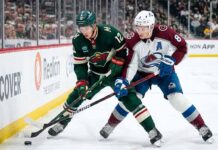 Minnesota Wild's Matt Boldy and Colorado Avalanche's Cale Makar battle for the puck in a crucial NHL playoff game.