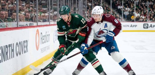 Minnesota Wild's Matt Boldy and Colorado Avalanche's Cale Makar battle for the puck in a crucial NHL playoff game.