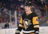 Why Buffalo Sabres Defenseman Bowen Byram is the Perfect Trade Target for the Pittsburgh Penguins A medium shot of Bowen Byram (wearing number 4) in his blue and gold Buffalo Sabres home jersey, holding a CCM hockey stick on the ice during a game.