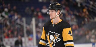Why Buffalo Sabres Defenseman Bowen Byram is the Perfect Trade Target for the Pittsburgh Penguins A medium shot of Bowen Byram (wearing number 4) in his blue and gold Buffalo Sabres home jersey, holding a CCM hockey stick on the ice during a game.