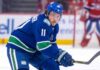 Brendan Gallagher Trade Rumors: Vancouver Canucks & Montreal Canadiens High-quality visualization of Brendan Gallagher wearing a Vancouver Canucks blue and green uniform on the ice, illustrating a rumored NHL trade from the Montreal Canadiens.