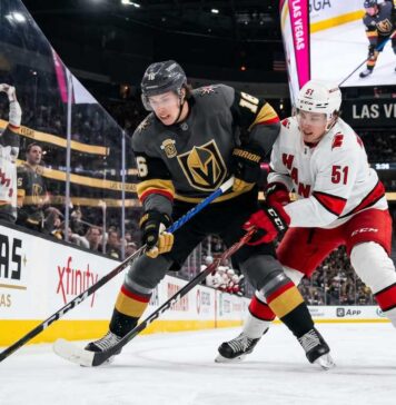 How to Watch Carolina Hurricanes vs Vegas Golden Knights Game 4 | TV & Prediction Stanley Cup Final Game 4 action: Mitch Marner (grey jersey, #16) of the Vegas Golden Knights and Jackson Blake (white jersey, #51) of the Carolina Hurricanes battle on the ice at T-Mobile Arena.