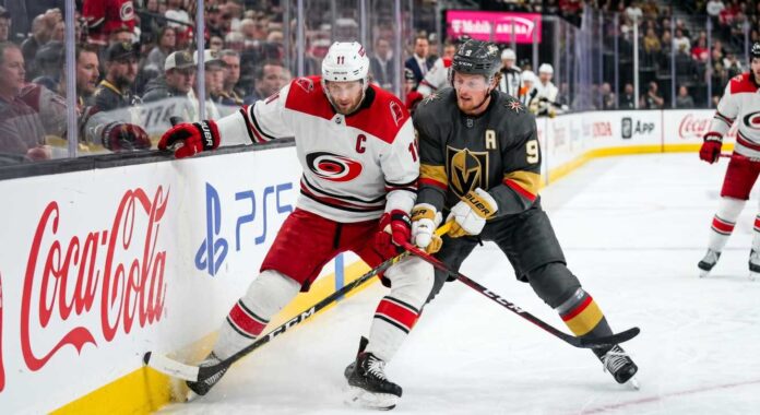 carolina-hurricanes-vs-vegas-golden-knights-game-6-live-tv Carolina Hurricanes and Vegas Golden Knights puck battle featuring captains Jordan Staal (#11, 'C') and Jack Eichel (#9, 'A') along the boards during Game 6 of the 2026 Stanley Cup Final.