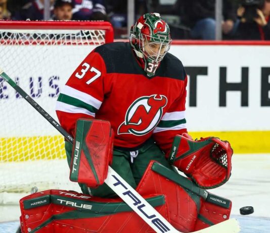 Will the New Jersey Devils Trade for Winnipeg Jets Goalie Connor Hellebuyck? Connor Hellebuyck (No. 37) wearing a custom New Jersey Devils home jersey, mask, and goaltending pads, posed in a butterfly save position during an NHL hockey game, a visualization of potential trade rumors.