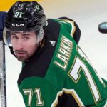 Dylan Larkin Trade Rumors: Detroit Red Wings Star Linked to Dallas Stars Description: A photorealistic image of Detroit Red Wings captain Dylan Larkin in a Victory Green Dallas Stars home hockey jersey (number 71) and black helmet, holding a hockey stick. This image was generated to visualize trade rumors linking Larkin to Dallas.