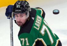 Dylan Larkin Trade Rumors: Detroit Red Wings Star Linked to Dallas Stars Description: A photorealistic image of Detroit Red Wings captain Dylan Larkin in a Victory Green Dallas Stars home hockey jersey (number 71) and black helmet, holding a hockey stick. This image was generated to visualize trade rumors linking Larkin to Dallas.