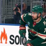 A digitally altered image showing Dylan Larkin wearing a green Minnesota Wild home jersey and helmet, reflecting ongoing NHL trade rumors.