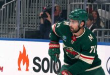 A digitally altered image showing Dylan Larkin wearing a green Minnesota Wild home jersey and helmet, reflecting ongoing NHL trade rumors.