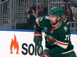 A digitally altered image showing Dylan Larkin wearing a green Minnesota Wild home jersey and helmet, reflecting ongoing NHL trade rumors.