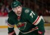 Photorealistic composite image showing NHL center Dylan Larkin in a Minnesota Wild home jersey with number 71 and a captain’s “C”, visualizing trade rumors linking him to Minnesota.
