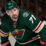 Dylan Larkin Trade Rumors: Is He Going to the Minnesota Wild? Photorealistic composite image showing NHL center Dylan Larkin in a Minnesota Wild home jersey with number 71 and a captain’s “C”, visualizing trade rumors linking him to Minnesota.