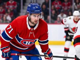Montreal Canadiens forward Dylan Larkin (number 71) is captured in a red home jersey, skating with the puck in a high-quality NHL action photograph. The photo highlights his focus and skill, a key figure in recent trade speculation.