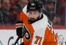 Detroit Red Wings captain Dylan Larkin wearing a Philadelphia Flyers home uniform and orange helmet in a hockey pose, illustrating recent NHL trade rumors linking him to Philly.