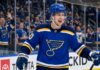 Elias Pettersson Trade Rumors: St. Louis Blues Linked to Vancouver Canucks Center Smiling Elias Pettersson wearing a St. Louis Blues home jersey with Blue Note logo and #40 helmet, celebrating on ice with cheering crowd; speculative trade visualization.