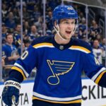 Elias Pettersson Trade Rumors: St. Louis Blues Linked to Vancouver Canucks Center Smiling Elias Pettersson wearing a St. Louis Blues home jersey with Blue Note logo and #40 helmet, celebrating on ice with cheering crowd; speculative trade visualization.