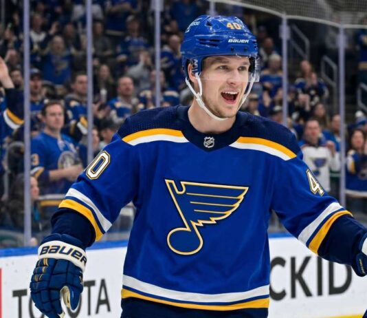 Elias Pettersson Trade Rumors: St. Louis Blues Linked to Vancouver Canucks Center Smiling Elias Pettersson wearing a St. Louis Blues home jersey with Blue Note logo and #40 helmet, celebrating on ice with cheering crowd; speculative trade visualization.
