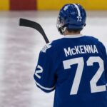 Gavin McKenna wearing a blue Toronto Maple Leafs home jersey with number 72 and the numbered blue helmet, seen from behind on an ice rink, viewed as the projected #1 overall pick for the 2026 NHL Draft.