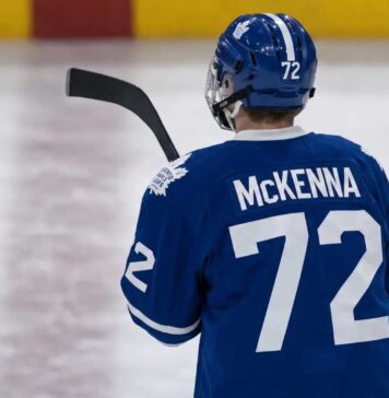 Gavin McKenna wearing a blue Toronto Maple Leafs home jersey with number 72 and the numbered blue helmet, seen from behind on an ice rink, viewed as the projected #1 overall pick for the 2026 NHL Draft.
