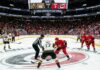 Vegas Golden Knights and Carolina Hurricanes center ice faceoff during Period 1 of the 2026 Stanley Cup Final Game 2, showing a packed arena and scoreboard.