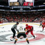 Vegas Golden Knights and Carolina Hurricanes center ice faceoff during Period 1 of the 2026 Stanley Cup Final Game 2, showing a packed arena and scoreboard.