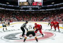 Vegas Golden Knights and Carolina Hurricanes center ice faceoff during Period 1 of the 2026 Stanley Cup Final Game 2, showing a packed arena and scoreboard.