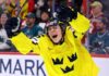 Team Sweden's Ivar Stenberg, wearing the iconic yellow and blue 'Tre Kronor' jersey with the number 15 and Svenska Spel logo, celebrating with a primal roar, raising his gloves and stick in triumph after scoring a goal during a hockey game, as San Jose Sharks fans look on in the background.