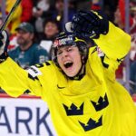 San Jose Sharks 2026 NHL Draft: Ivar Stenberg vs. Trade Scenarios Team Sweden's Ivar Stenberg, wearing the iconic yellow and blue 'Tre Kronor' jersey with the number 15 and Svenska Spel logo, celebrating with a primal roar, raising his gloves and stick in triumph after scoring a goal during a hockey game, as San Jose Sharks fans look on in the background.