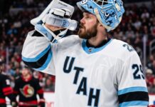 Jacob Markstrom Trade Rumors: Utah Mammoth Linked to Devils Goalie A close-up photograph of Jacob Markstrom, New Jersey Devils goaltender, wearing his white away jersey and custom mask while drinking from a water bottle on the ice, amidst trade rumors.