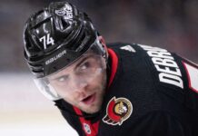 Jake DeBrusk Trade Rumors: Ottawa Senators & Vancouver Canucks Linked A close-up view visualizing Jake DeBrusk in a black Ottawa Senators hockey jersey and black helmet with the number 74.