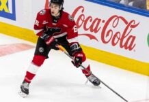 Maddox Dagenais #16 of the Quebec Remparts QMJHL, a 6'4" center, skating with the puck. Background rink boards with large Coca-Cola logo. Image from an article on Utah Mammoth NHL Draft pick analysis.