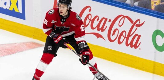 Maddox Dagenais #16 of the Quebec Remparts QMJHL, a 6'4" center, skating with the puck. Background rink boards with large Coca-Cola logo. Image from an article on Utah Mammoth NHL Draft pick analysis.