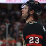 Ottawa Senators Trade Rumors: Anaheim Ducks’ Mason McTavish Linked to Sens A close-up profile view of NHL hockey player Mason McTavish #23 wearing a black Ottawa Senators jersey and helmet, looking focused on the ice.