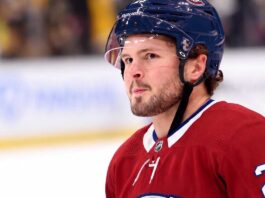 A detailed close-up view of NHL player Mason McTavish wearing a red Montreal Canadiens (Habs) home jersey with the number 23 on the shoulder and a blue Bauer helmet with the 'CH' logo, standing on an ice rink.