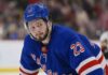Mason McTavish wearing a New York Rangers home jersey amid trade rumors involving the Anaheim Ducks