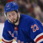 Mason McTavish wearing a New York Rangers home jersey amid trade rumors involving the Anaheim Ducks