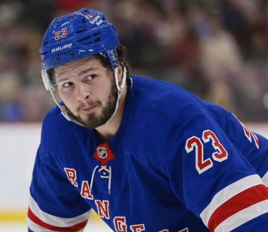 Mason McTavish wearing a New York Rangers home jersey amid trade rumors involving the Anaheim Ducks