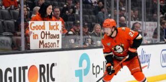 Ottawa Senators Trade Rumors: Targeting Ducks’ Mason McTavish Anaheim Ducks forward Mason McTavish skating along the boards while a fan in the stands holds a sign reading "Good luck in Ottawa Mason!" amidst Ottawa Senators trade rumors.