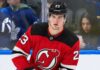 A close-up photo of hockey player Matthew Knies wearing a red New Jersey Devils home jersey, number 23, illustrative of the blockbuster trade rumor discussed in the article regarding a potential move from the Toronto Maple Leafs.