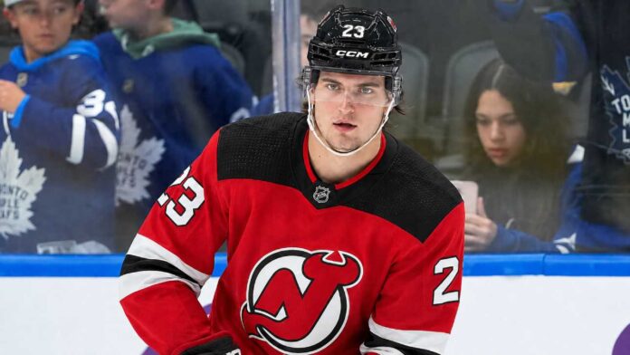A close-up photo of hockey player Matthew Knies wearing a red New Jersey Devils home jersey, number 23, illustrative of the blockbuster trade rumor discussed in the article regarding a potential move from the Toronto Maple Leafs.