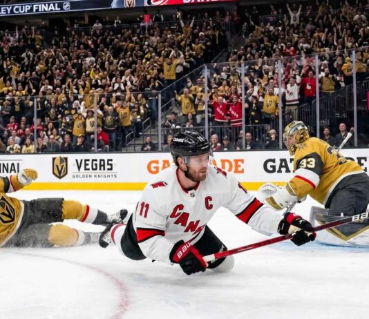 Latest NHL News and NHL Scores: Stanley Cup Final Game 4 Recap Jordan Staal, wearing number 11 and a "C" on his white away jersey, falling to the ice while scoring a diving backhand goal with his Bauer stick, against the Vegas Golden Knights in Game 4 of the 2026 Stanley Cup Final. He is sliding towards the right on the ice, and the puck is visibly entering the net on the far right of the photo.