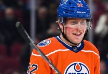 Patrik Laine smiling while wearing an Edmonton Oilers home jersey and blue helmet with visor, visualizing free agency rumors linking him to the Oilers.