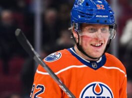 Patrik Laine smiling while wearing an Edmonton Oilers home jersey and blue helmet with visor, visualizing free agency rumors linking him to the Oilers.