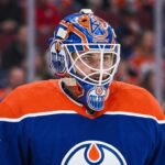 Edmonton Oilers Trade Rumors: Montreal Canadiens Goalie Samuel Montembeault Detailed photo illustration of Montreal Canadiens goalie Samuel Montembeault, looking intense from his crease, with his mask and gear custom-edited to display prominent Edmonton Oilers logos and team colors, visualizing ongoing NHL trade rumors.