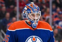 Edmonton Oilers Trade Rumors: Montreal Canadiens Goalie Samuel Montembeault Detailed photo illustration of Montreal Canadiens goalie Samuel Montembeault, looking intense from his crease, with his mask and gear custom-edited to display prominent Edmonton Oilers logos and team colors, visualizing ongoing NHL trade rumors.