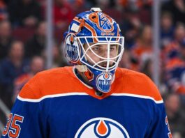 Edmonton Oilers Trade Rumors: Montreal Canadiens Goalie Samuel Montembeault Detailed photo illustration of Montreal Canadiens goalie Samuel Montembeault, looking intense from his crease, with his mask and gear custom-edited to display prominent Edmonton Oilers logos and team colors, visualizing ongoing NHL trade rumors.