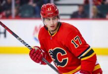Action photograph of young right-shot defenseman Simon Nemec wearing a Calgary Flames red home jersey with number 17, holding a hockey stick on the ice.
