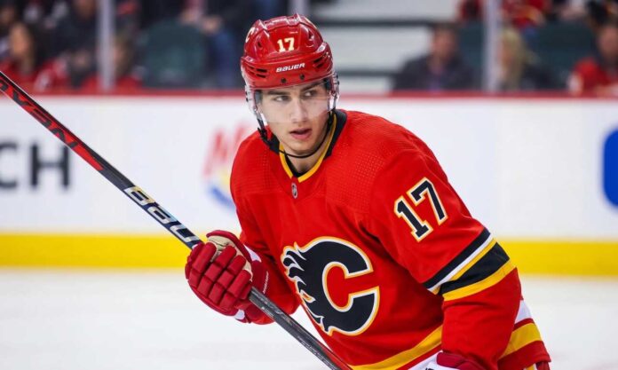 simon-nemec-calgary-flames-trade Action photograph of young right-shot defenseman Simon Nemec wearing a Calgary Flames red home jersey with number 17, holding a hockey stick on the ice.