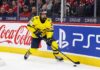 Viggo Björck, a top prospect for the Seattle Kraken in the 2026 NHL Draft, skating with the puck in his yellow Team Sweden number 21 jersey during an international game.